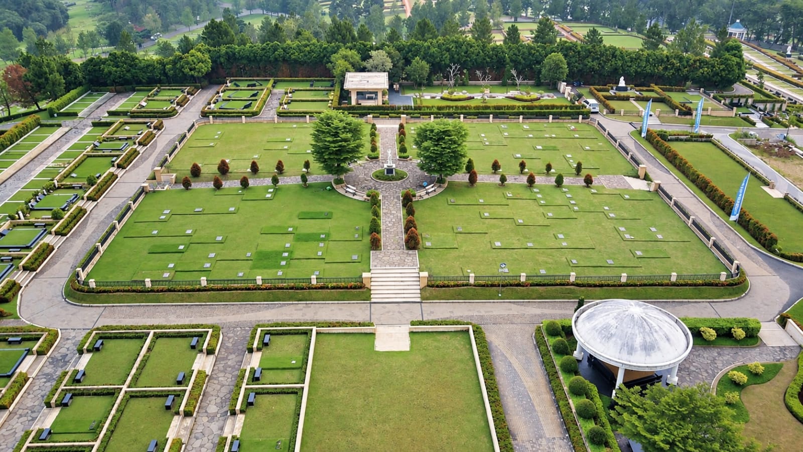 Pemandangan udara taman utama San Diego Hills Memorial Park, lahan makam tertata rapi mengelilingi monumen tengah