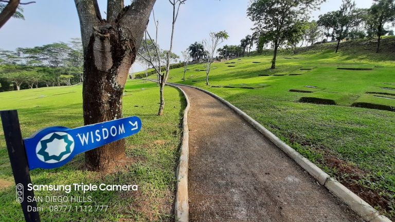 Papan penanda Blok Wisdom bernuansa Islami dan jalan setapak menuju taman makam berumput hijau di Five Pillars Garden San Diego Hills