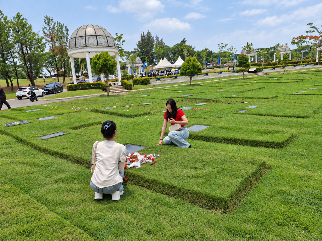 Ziarah keluarga di San Diego Hills: menabur bunga segar di makam di taman rumput yang tertata, dengan gazebo dan tenda acara di latar belakang