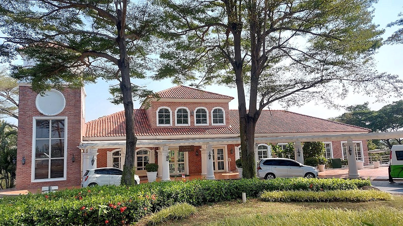 Kantor Marketing San Diego Hills bergaya country club dengan menara jam dan pepohonan rindang